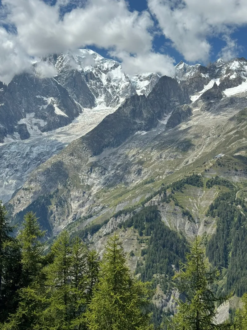 A hiker on the trail with the Mont Blanc massif rising behind